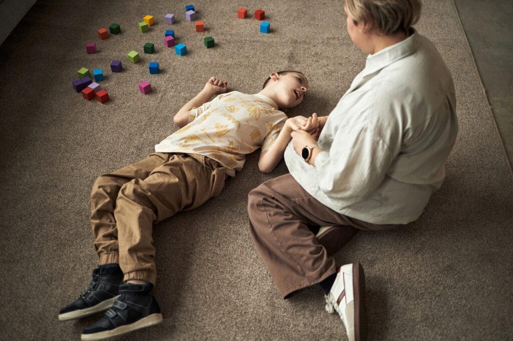 Child with Disability Lying on Carpet Playing with Colorful Blocks
