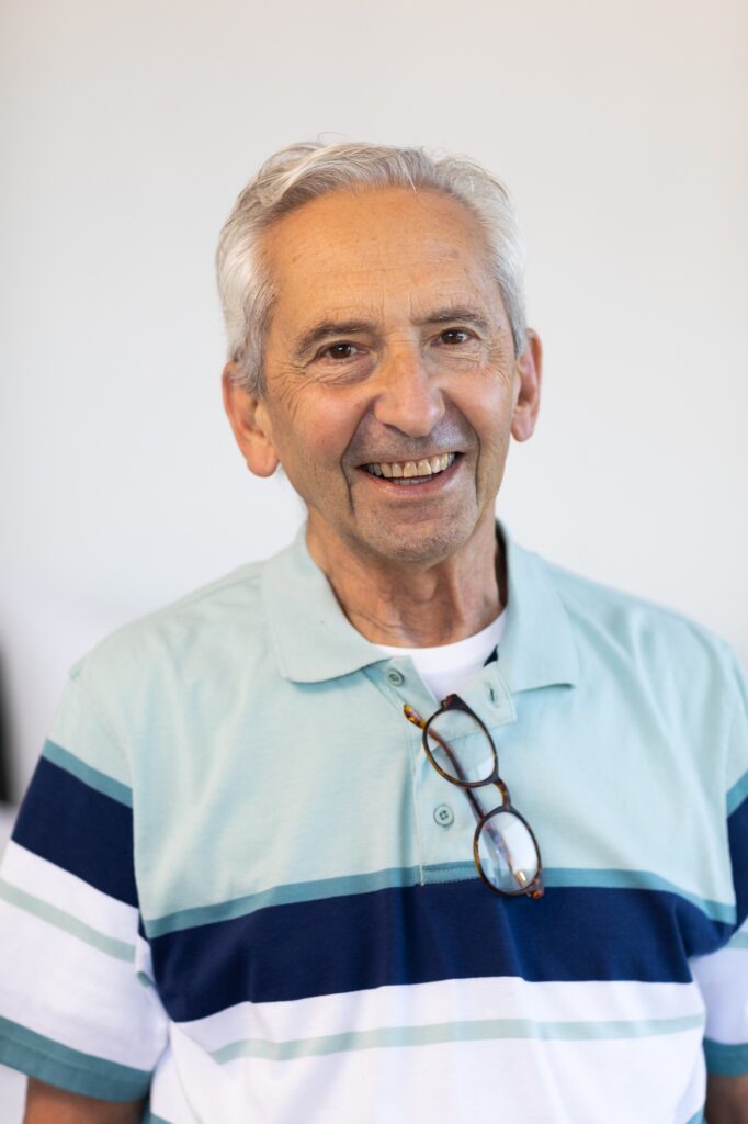 Close-up portrait of cheerful caucasian senior man with eyeglasses against white wall at home