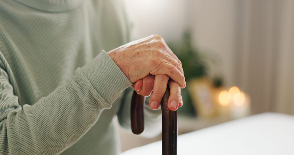 Hands, elderly and walking stick, person with disability and mockup space with closeup. Senior care